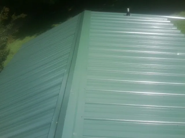 New green metal panels meeting at the ridge of a roof — Flat Roof Repair work by our crew in West Islip