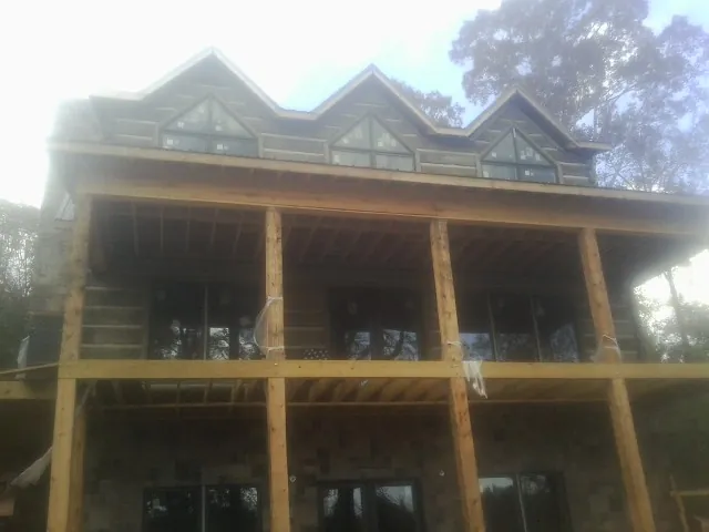 Dormers and porch framing on a large log home under construction — Roof Coating work by our crew in West Islip