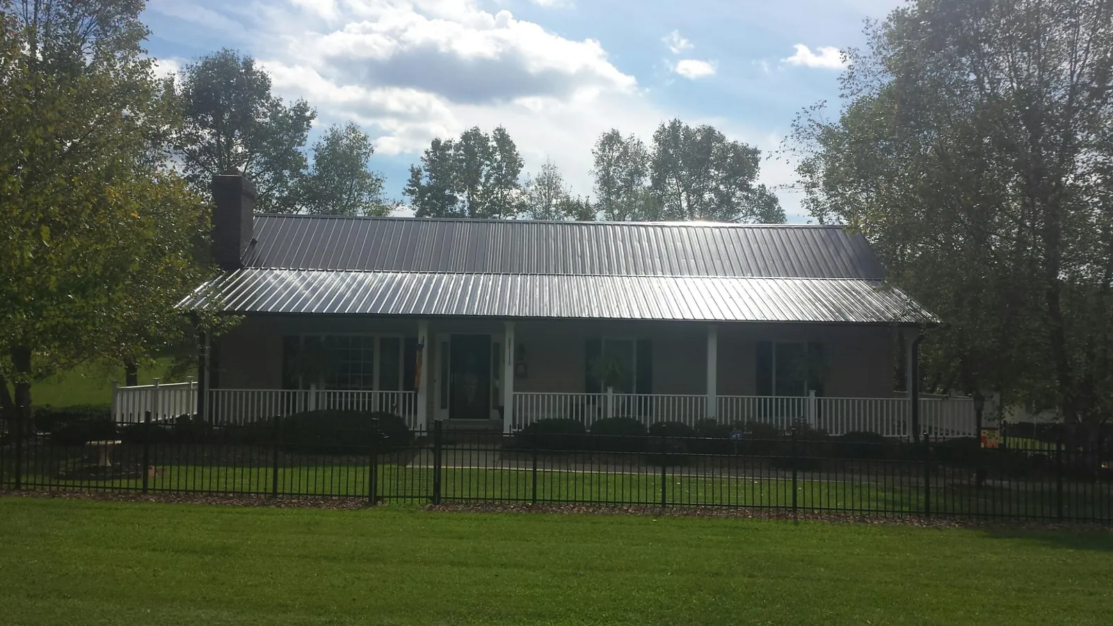 Gray metal roof on a brick ranch with a full width front porch — Gutter Guard Installation work by our crew in West Islip