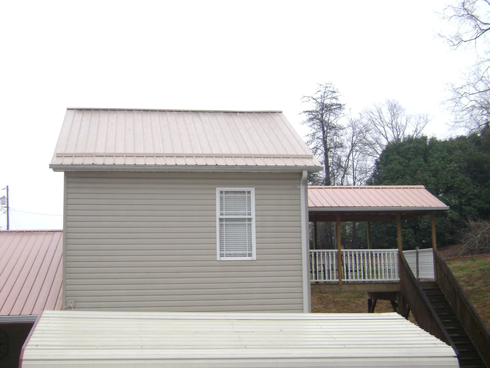 Tan metal roofs on a two story addition and attached porch, from a Roof Replacement job in West Islip