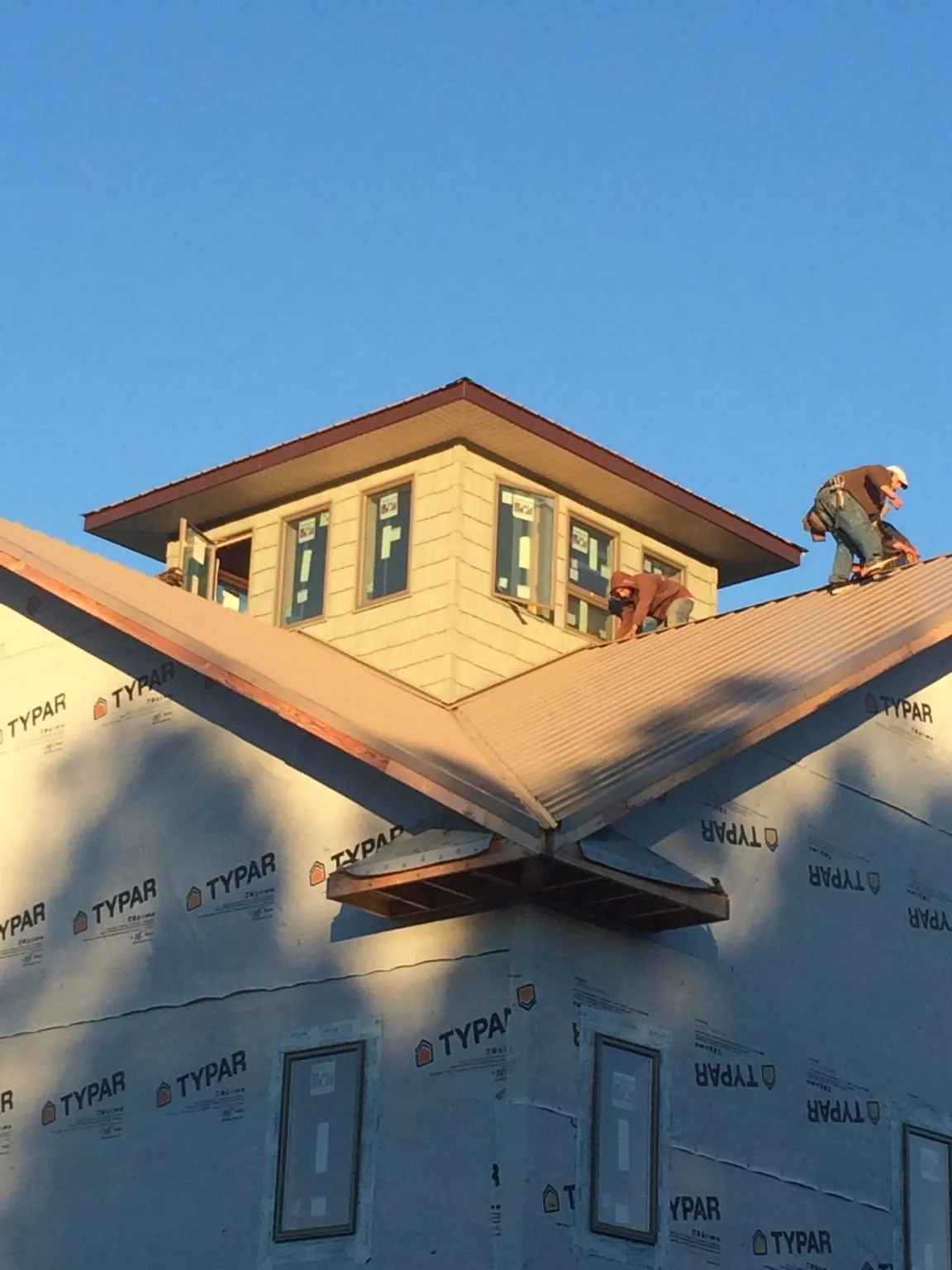 Roofers working around a rooftop cupola on a new metal roof at sunset — Roof Waterproofing in West Islip by Roofing Brothers